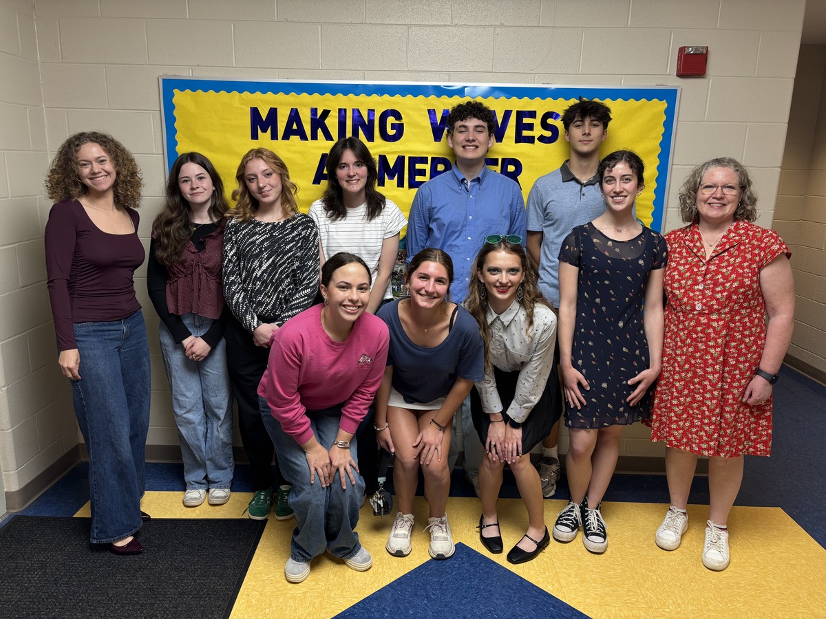 Mock trial students and the advisor pose for a group photo in a school hallway